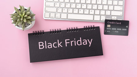 Black friday sale concept with credit card and computer keyboard on pink background, top view