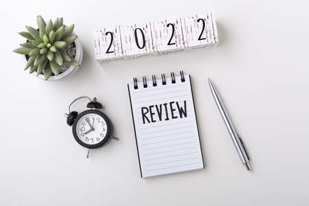 2022 Review concept with notebook and clock on white table background, top viewの写真素材
