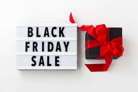 Black friday sale on light box with black gift box and red bow on white background, flat layの写真素材
