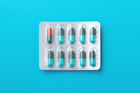 Capsule pills, medicine in pack on blue background, top view