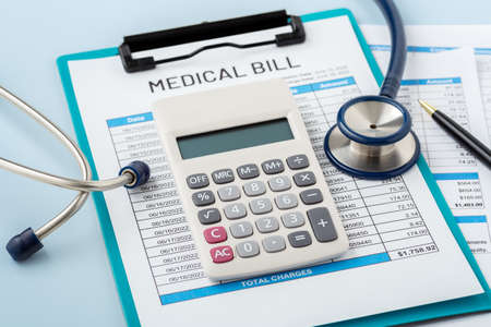 Calculator on medical bill with doctor stethoscope, healthcare cost, hospital payment, on blue backgroundの写真素材