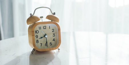 Alarm clock on marble table with light window backgroundの写真素材