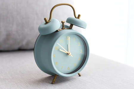 Pastel blue vintage clock on fabric couch near windowの写真素材