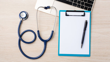 Doctor desk with stethoscope, clipboard and laptop, top viewの写真素材