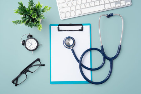 Doctor desk with stethoscope, clipboard and computer keyboard on blue background, top view