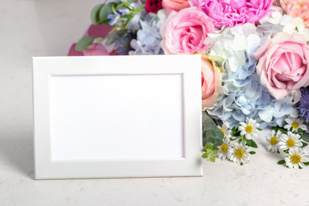 Horizontal white photo frame with flower bouquet on marble tableの写真素材