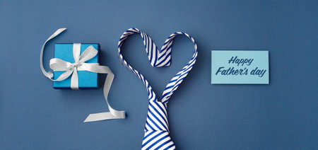 Happy fathers day concept, tie in heart shape with gift box and card on blue background, top viewの写真素材