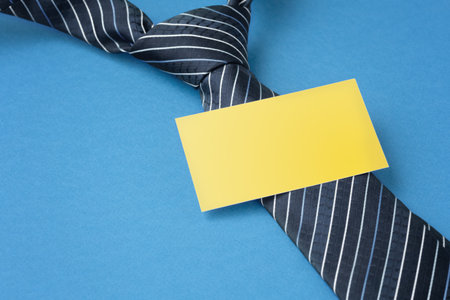 Blank yellow  business card with tie on blue backgroundの写真素材