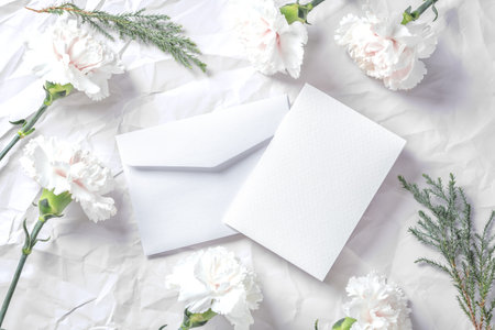 White paper card and envelope with flowers on crumpled texture, top viewの写真素材