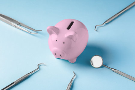 Pink piggy bank with dental instruments on blue background, dental health care and treatment cost