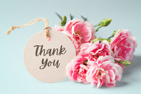 Thank you tag with pink carnation flower bouquet on blue backgroundの写真素材