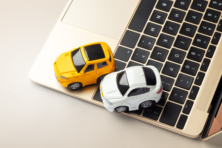 Toy car on laptop on gold table, online selling, buying car, auto insuranceの写真素材