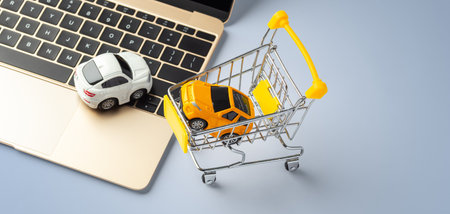 Car toy on laptop with shopping cart on blue background, copy spaceの写真素材