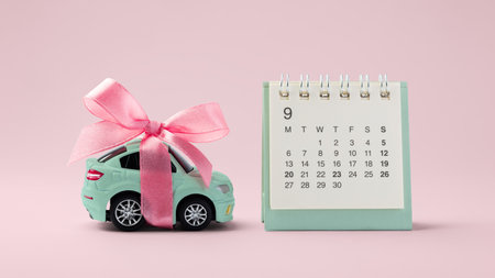 Car toy with bow and calendar on pink backgroundの写真素材