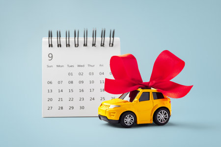 Car gift with red bow and calendar on blue backgroundの写真素材