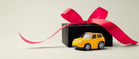 Car toy with black gift box and red bow on beige background, copy spaceの写真素材