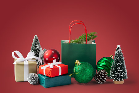 Christmas gift box and present with green christmas ball and decor on red background, copy spaceの写真素材