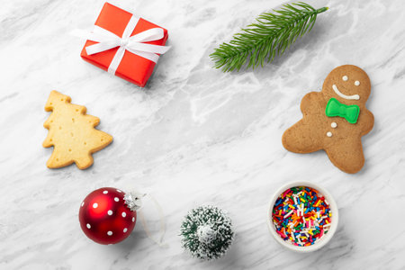 Christmas background with gingerbread man, red gift box and christmas decoration on marble table, top viewの写真素材