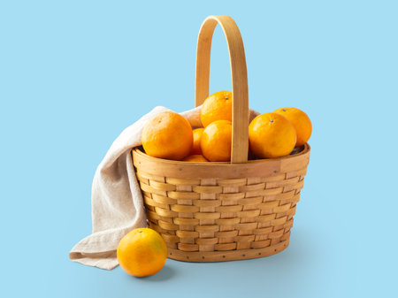 Oranges fruit in woven basket with linen napkin on blue backgroundの写真素材