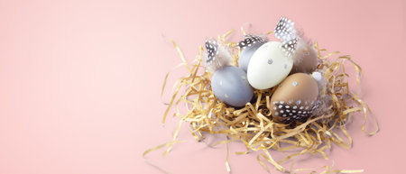 Easter eggs with feathers on gold glitter shredded paper on pink background, copy spaceの写真素材