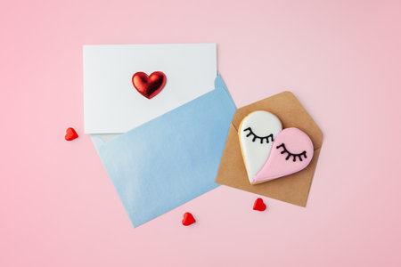 Card with heart in blue envelope and heart shaped cookie, valentines day, mothers day on pink background, top viewの写真素材