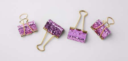 Gold binder clips with pink glitter on gray background, top viewの写真素材