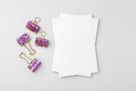 Blank white paper and pink glitter binder clips on grey background, top viewの写真素材