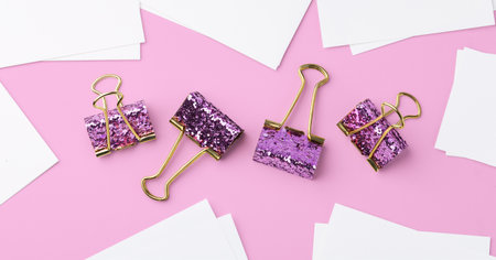 Pink glitter binder clips with white card on pink background, top viewの写真素材