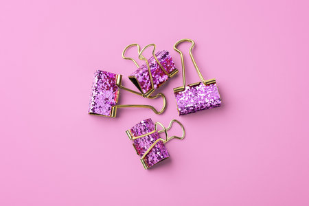 Gold paper clips with glitter on pink background, top viewの写真素材