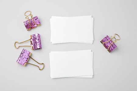 White paper note and pink glitter binder clips on gray background, top viewの写真素材