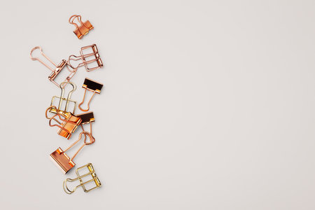 Gold and copper binder paper clip on light beige background, top view, copy spaceの写真素材