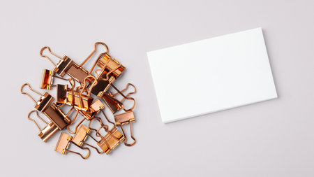 Heap of copper gold binder clips and memo note paper on light grey background, top viewの写真素材