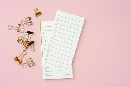 To do list paper with gold binder clip on pink background, top view, copy spaceの写真素材