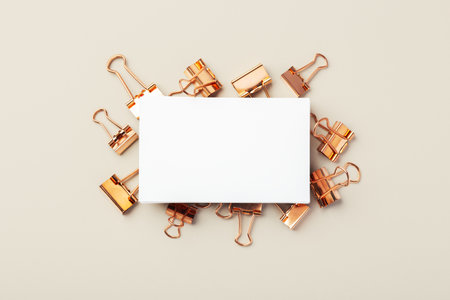 Business card on copper binder paper clips on beige background, mockup, top viewの写真素材