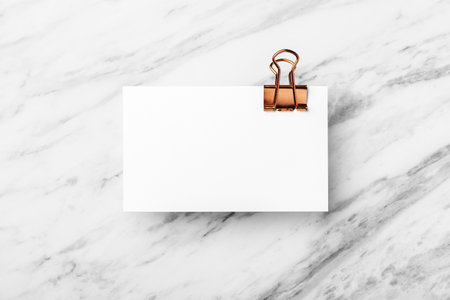 Business card with copper binder clip, mockup on white marble table background, top viewの写真素材