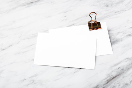 Business card with copper binder clip, mockup on white marble table backgroundの写真素材