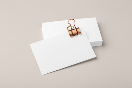 Blank business card with copper gold binder paper clip mockup on beige backgroundの写真素材