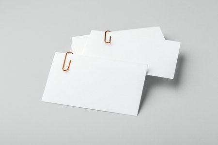 Blank white business card with copper gold clip mockup on light grey backgroundの写真素材