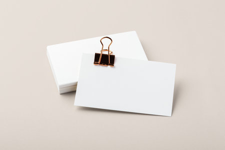 Blank business card with gold binder clip mockup on beige backgroundの写真素材
