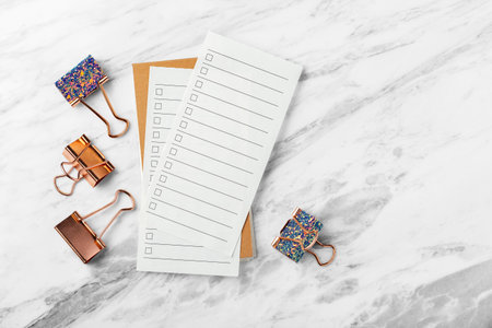 Check list paper with rose gold binder clip on marble table background, top view, copy spaceの写真素材