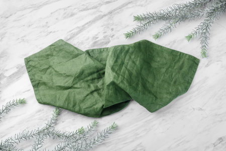 Green linen kitchen cloth on on white natural marble table with leaves, top viewの写真素材