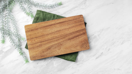 Wood plate board on green linen napkin on natural marble table, top view, copy spaceの写真素材