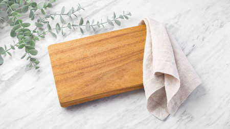 Wooden board with natural linen cloth napkin isolated on white marble table backgroundの写真素材