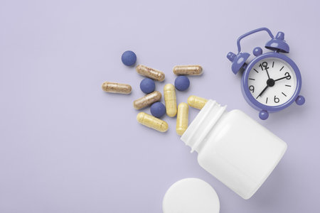 Supplement, vitamin for beauty spilling out of white bottle on pastel purple background, top view, copy spaceの写真素材