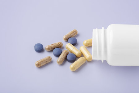 Natural supplement, beauty vitamin spilling out of medical bottle on pastel purple backgroundの写真素材
