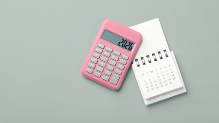 Pink calculator with 2026 and calendar on green background, new year financial resolutions, budget planning, top view copy spaceの写真素材