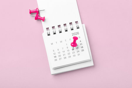 Calendar with pinned date on pink background, business reminder or appointment, holiday planning, top viewの写真素材