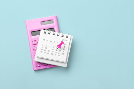 Calendar 2026 with pink pin on date and calculator on blue background, top view, copy spaceの写真素材