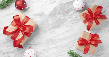 Christmas background, gift box with red bow ribbon with ball and leaves decor on marble table background, top view, copy spaceの写真素材