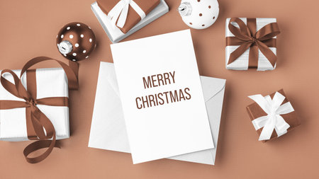 Merry christmas background, paper holiday greeting card with gift boxes and xmas ball on mocha mousse color background, top viewの写真素材